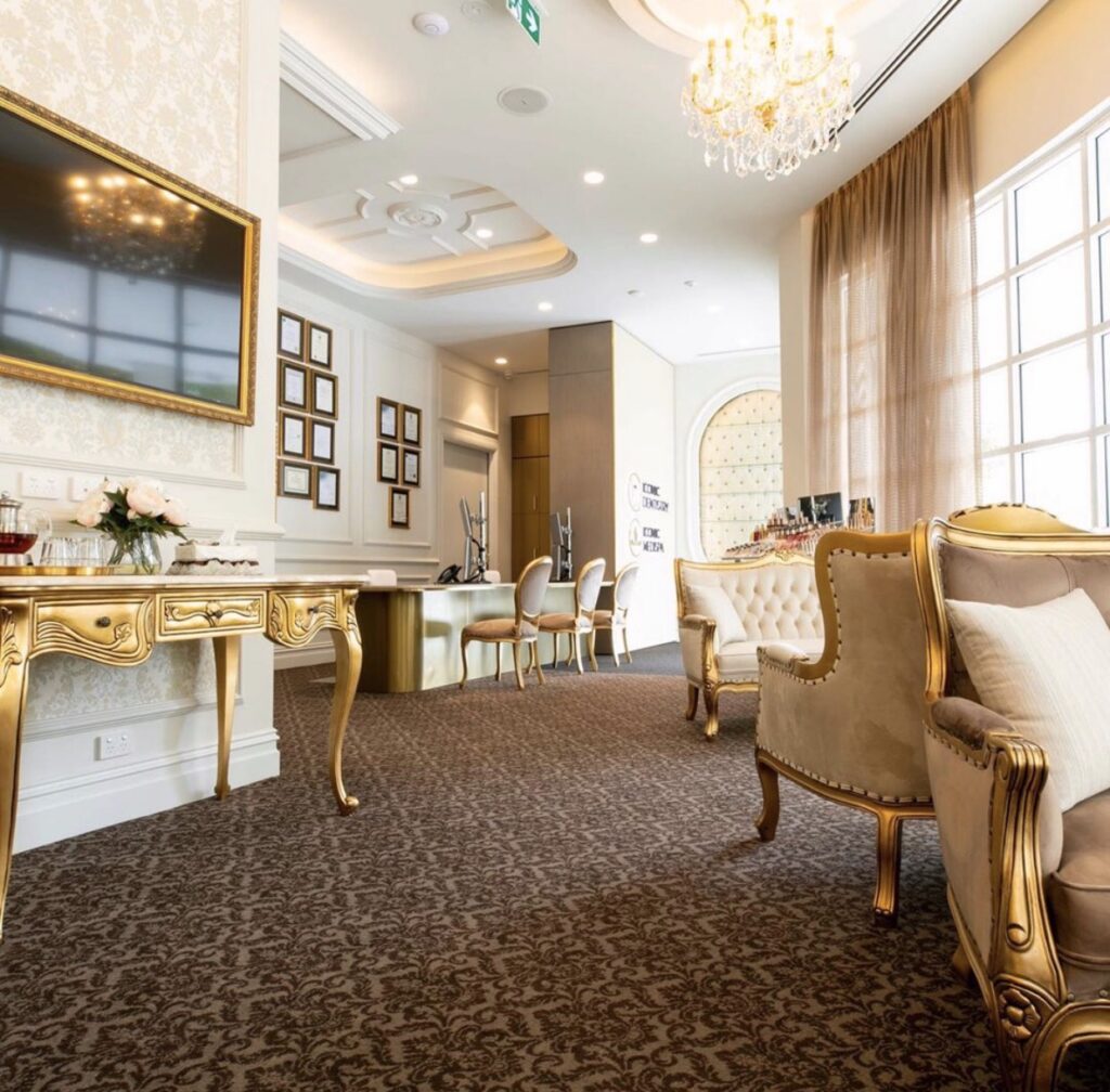 This is an image of the walk-in counter & beverage area featuring a custom-designed walk-in counter and french chairs paired with a console featuring a marble top