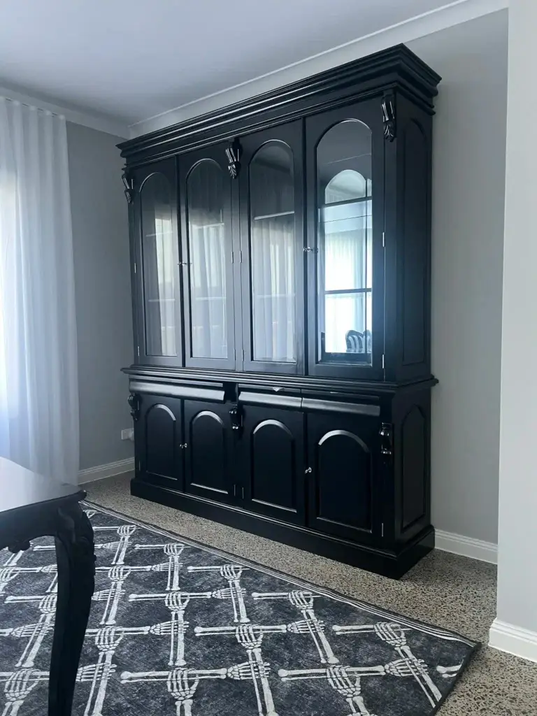 This is an image of a Black timber antique style black cabinet with glass windows on a polished concrete floor