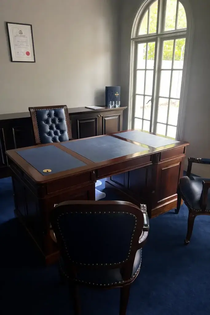 This is an image of a custom solid timber executive desk with deep navy leather writing surfaces and generous drawer storage, produced by The Antique Reproduction Shop