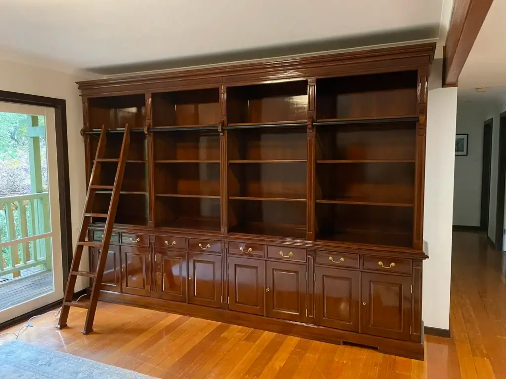 This is an image of an Antique style timber bookcase with a rolling ladder, crafted by The Antique Reproduction Shop