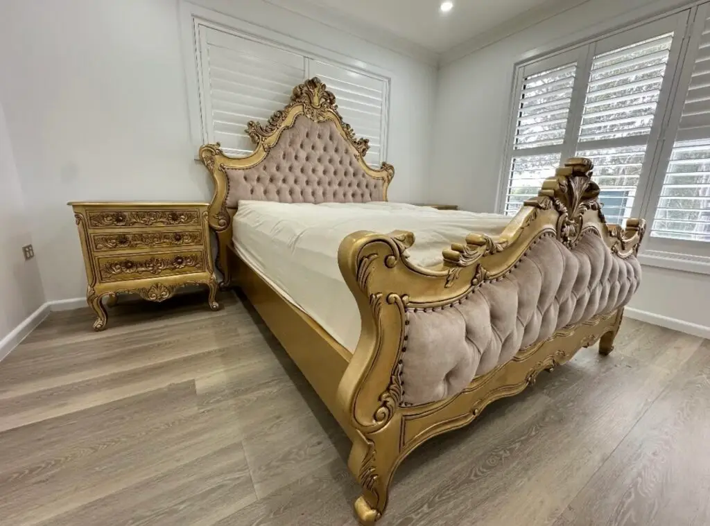 This is an image of a French Baroque upholstered bed in antique gold leaf with champagne fabric
