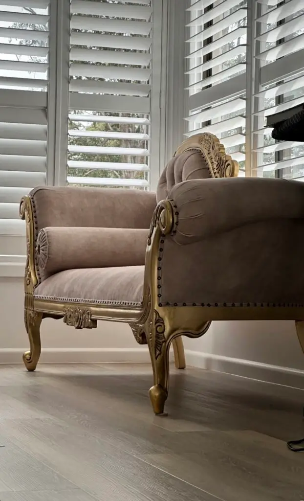 This is an image of an elegant French style chaise lounge in an antique gold finish with soft upholstered detailing